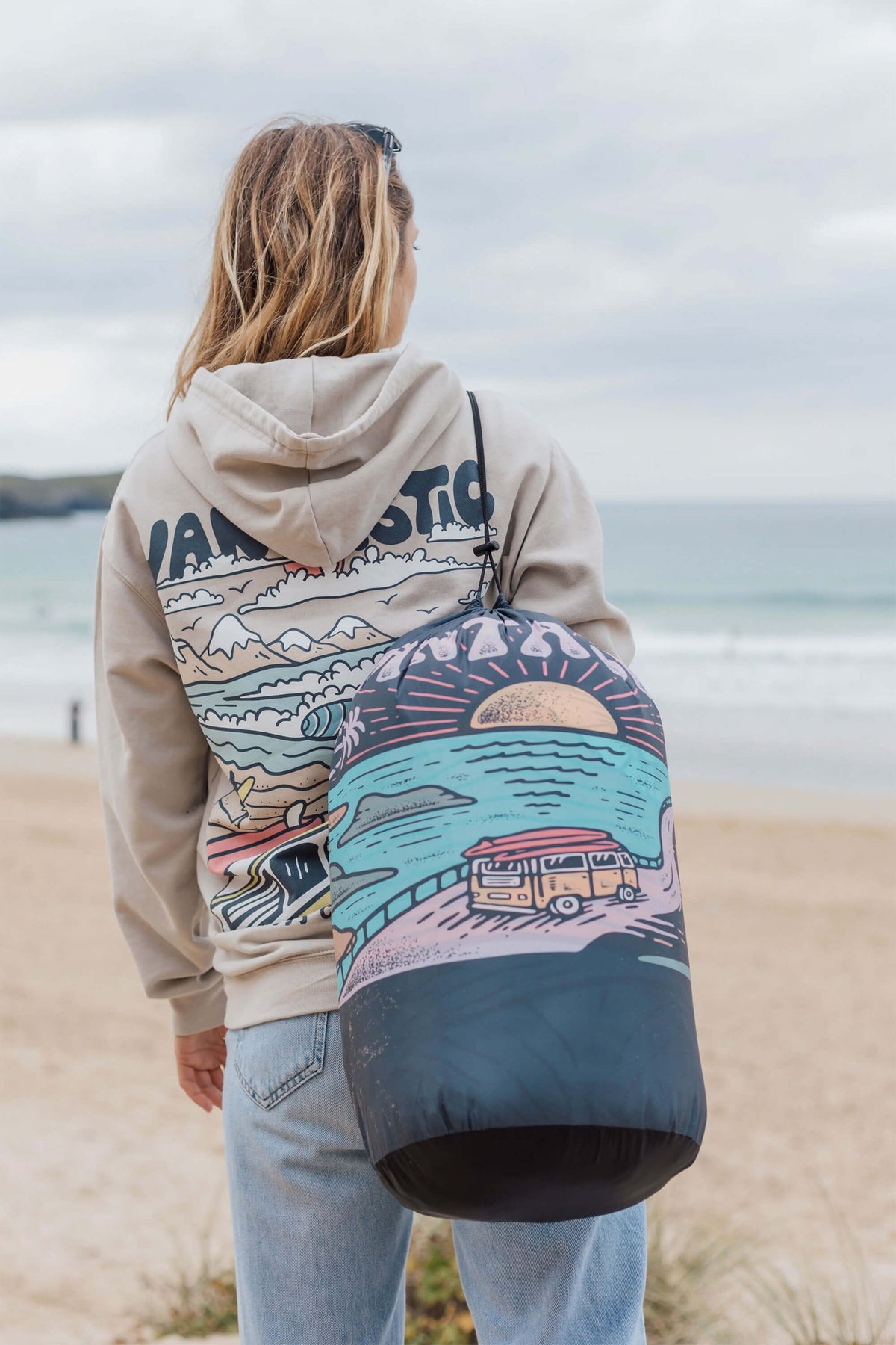 Person wearing a hoodie with a scenic design on a beach